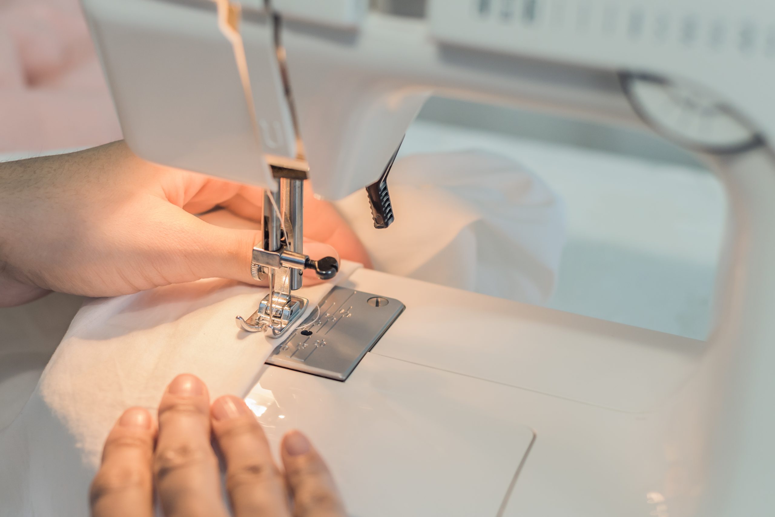 the-process-of-sewing-clothes-hands-on-sewing-machine-sewing-white-fabric